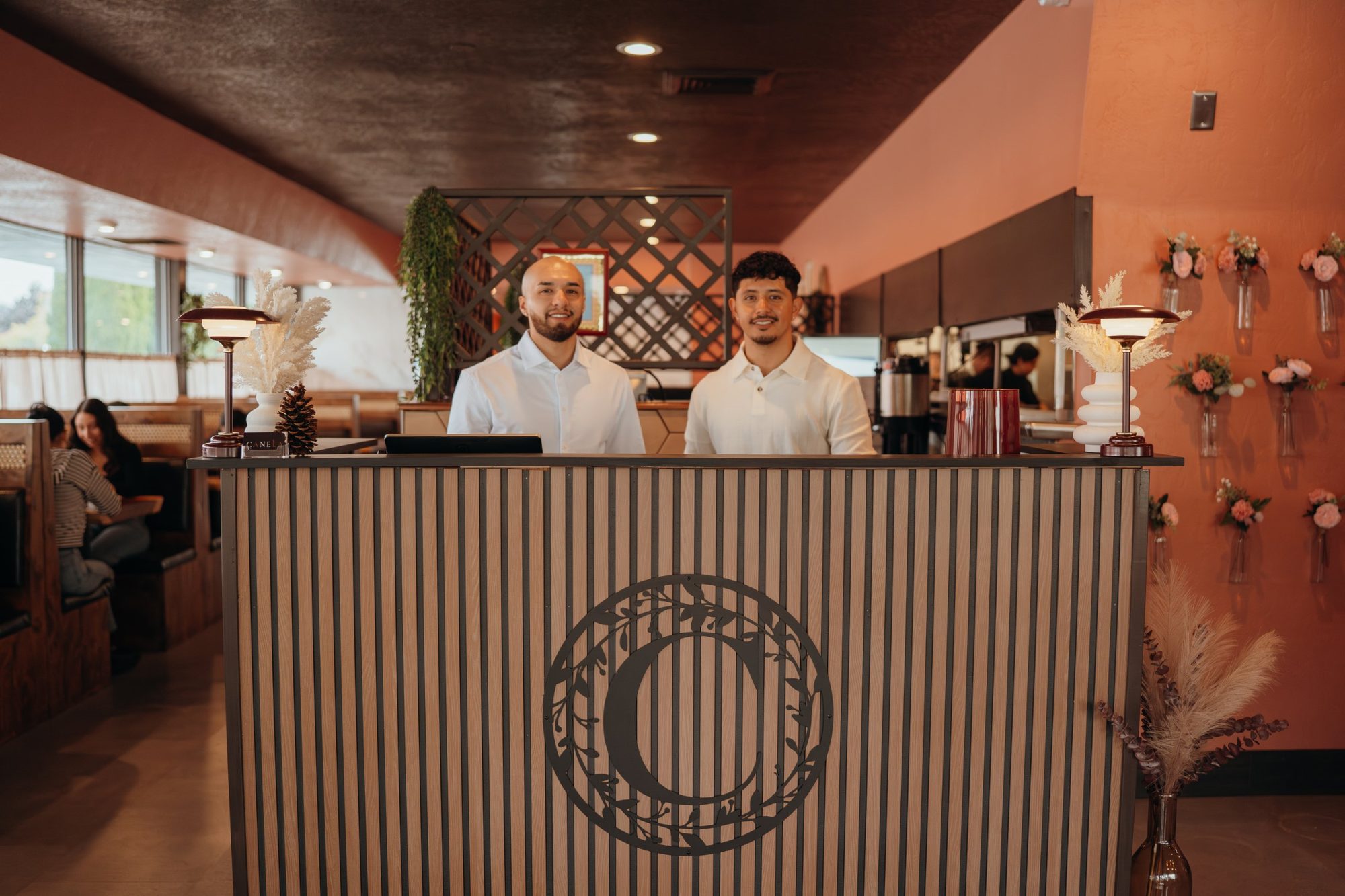 Saul and Jonny, founders of Canela Brunch & Cocktails, standing behind the Canela host stand